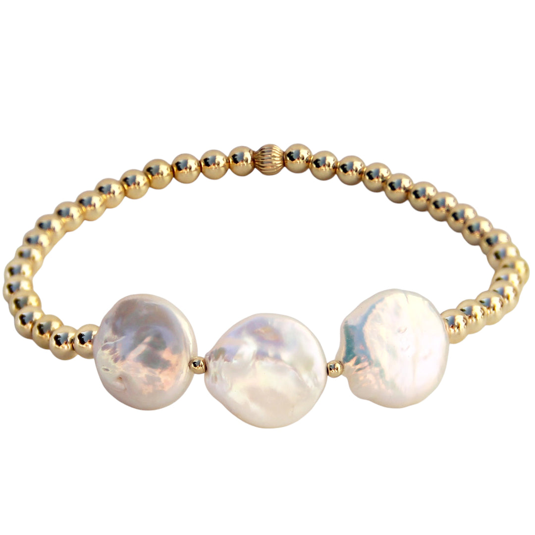 A gold beaded bracelet featuring three lustrous freshwater pearl coins, showcasing an elegant and natural design inspired by coastal beauty.