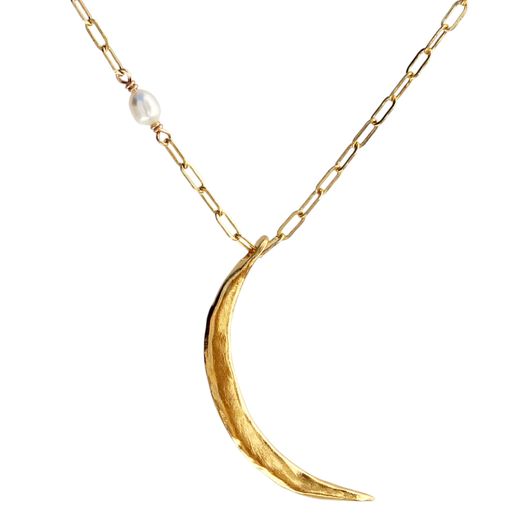 A large skinny gold crescent moon necklace with an organic texture, handcrafted in gold with a delicate pearl accent on a paperclip chain.