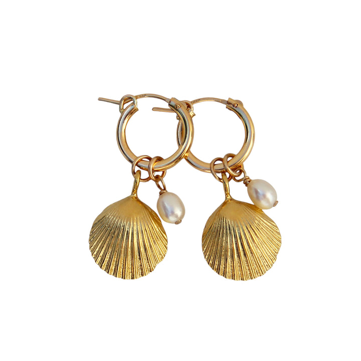 Product image of Golden Tide Shell Pearl Hoop Earrings by Blooming Lotus Jewelry. These gold hoops feature textured shell charms paired with delicate freshwater pearls, evoking a coastal, beach-inspired elegance. The combination of the shimmering gold and soft pearl accents adds a timeless, oceanic charm to these unique earrings.