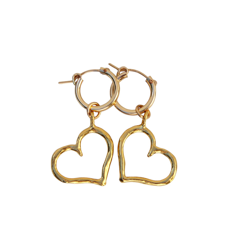 Product image of Heart of Gold Hoop Earrings by Blooming Lotus Jewelry. These gold hoop earrings feature an open, handcrafted heart charm, combining elegance with a playful, organic design. The slightly textured metal adds a unique, artisanal touch to these romantic, boho-inspired earrings.