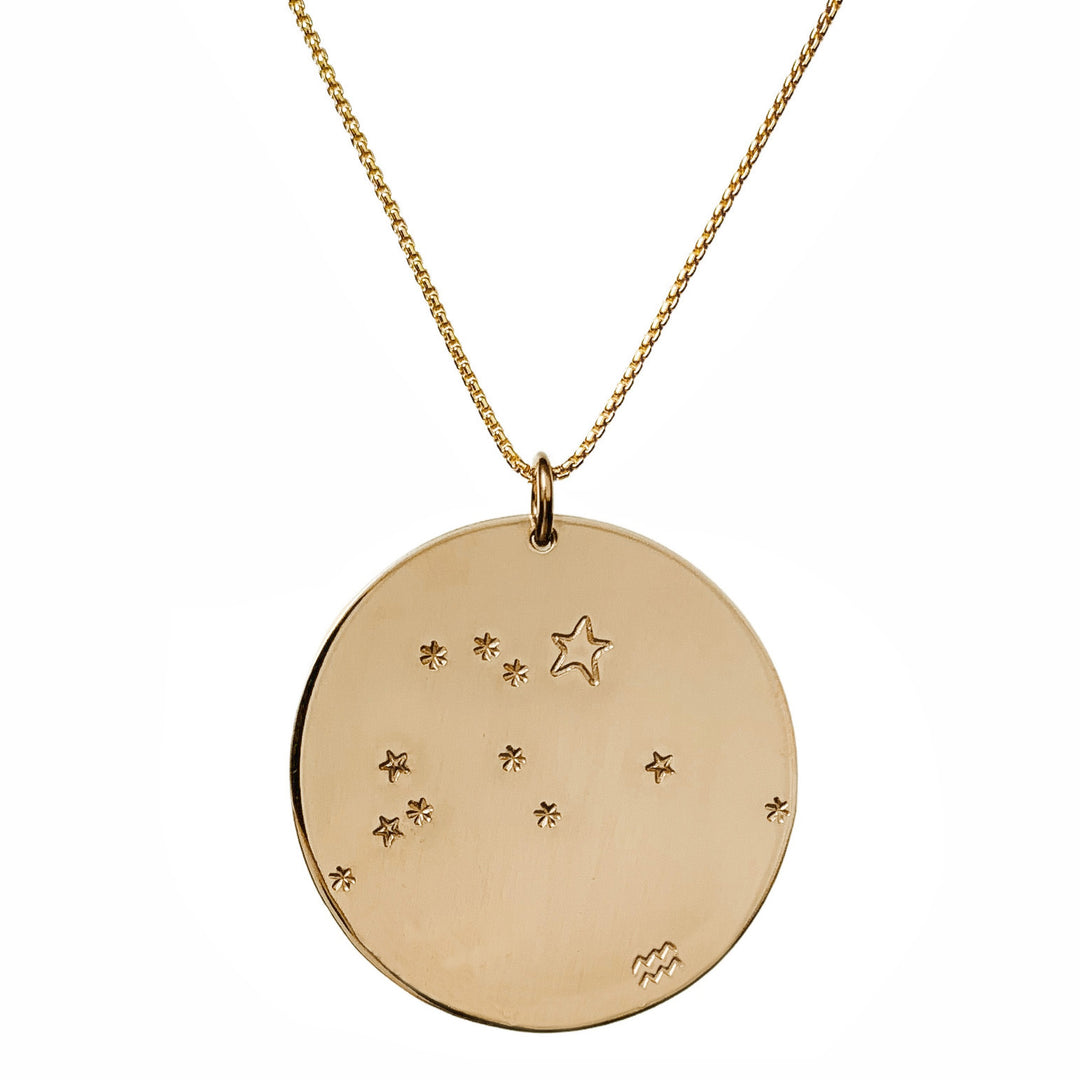 Close-up product photo of the Large Constellation Necklace in gold, featuring the Aquarius zodiac constellation stamped with star and dot patterns on a circular pendant, hanging from a gold chain. Perfect for a personalized and celestial-inspired jewelry statement.