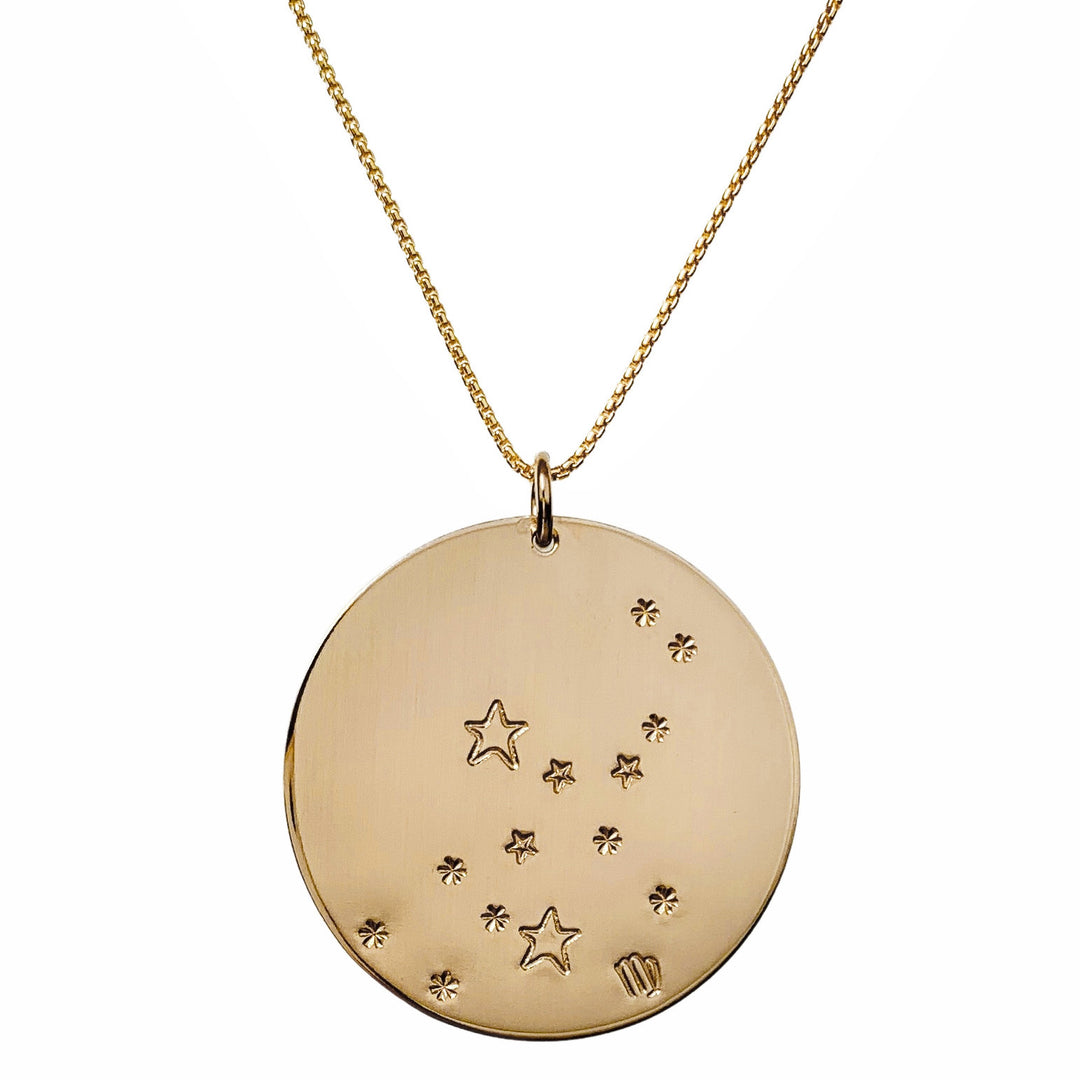 Close-up product photo of the Large Constellation Necklace in gold, featuring the Virgo zodiac constellation stamped with star and dot patterns on a circular pendant, hanging from a gold chain. Perfect for a personalized and celestial-inspired jewelry statement.