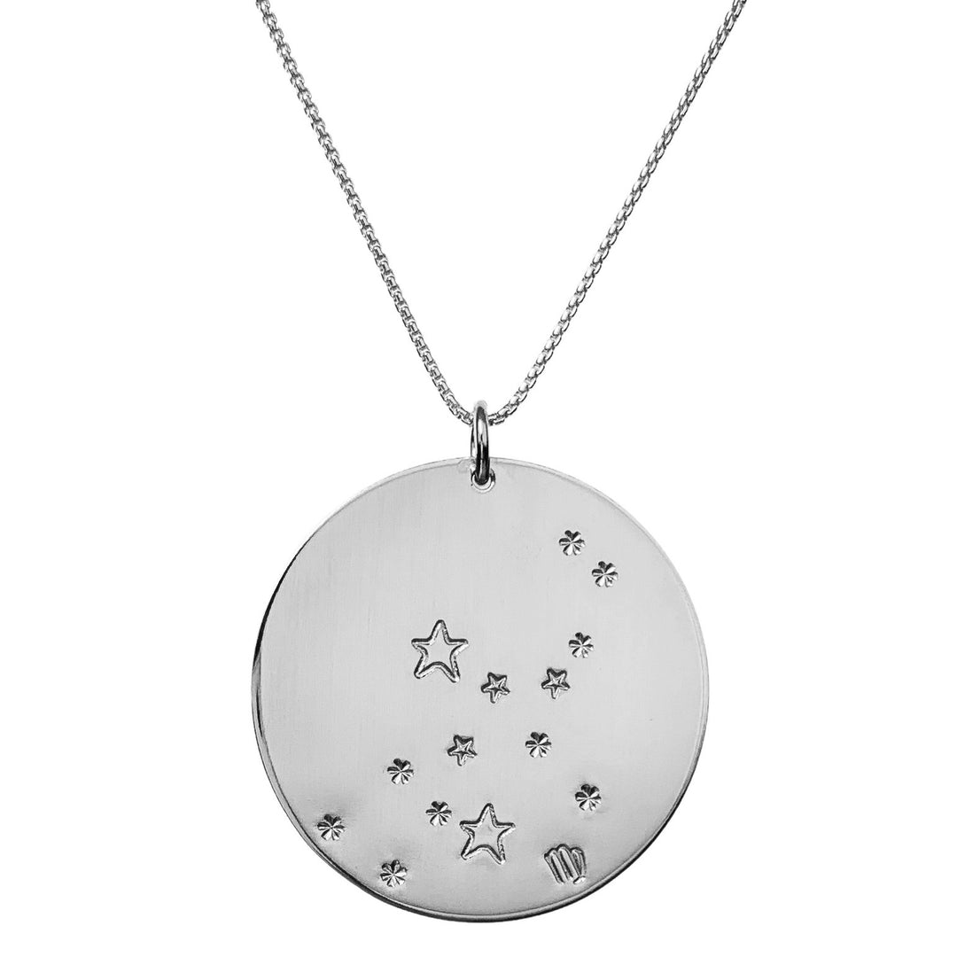 Close-up product photo of the Large Constellation Necklace in silver, featuring the Virgo zodiac constellation stamped with star and dot patterns on a circular pendant, hanging from a silver chain. Perfect for a personalized and celestial-inspired jewelry statement.