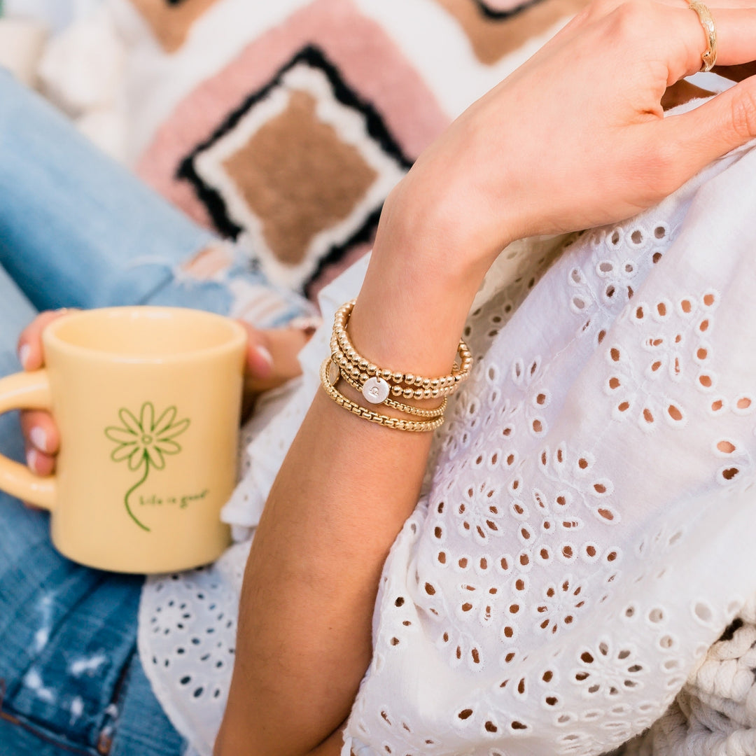 Gold beaded layering braclets on model charm initial zodiac - Blooming Lotus Jewelry