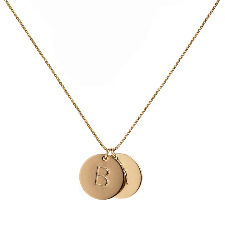 Gold hand-stamped initial disc necklace featuring two personalized pendants on a gold chain, perfect for custom gifts and everyday wear. Handmade by Blooming Lotus Jewelry.