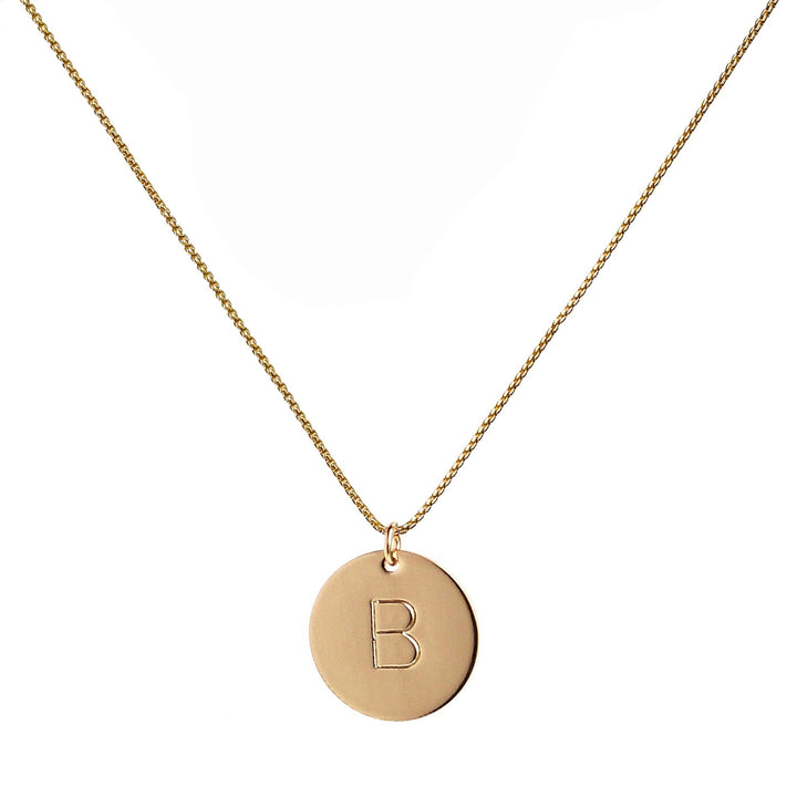 single gold initial disc coin pendant hanging from gold chain hand-stamped with capital B