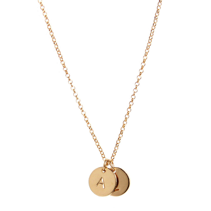 Gold necklace featuring two small round disc pendants, each hand-stamped with a single initial, 'A' and 'L,' hanging delicately from a fine chain for a minimalist and personalized style.