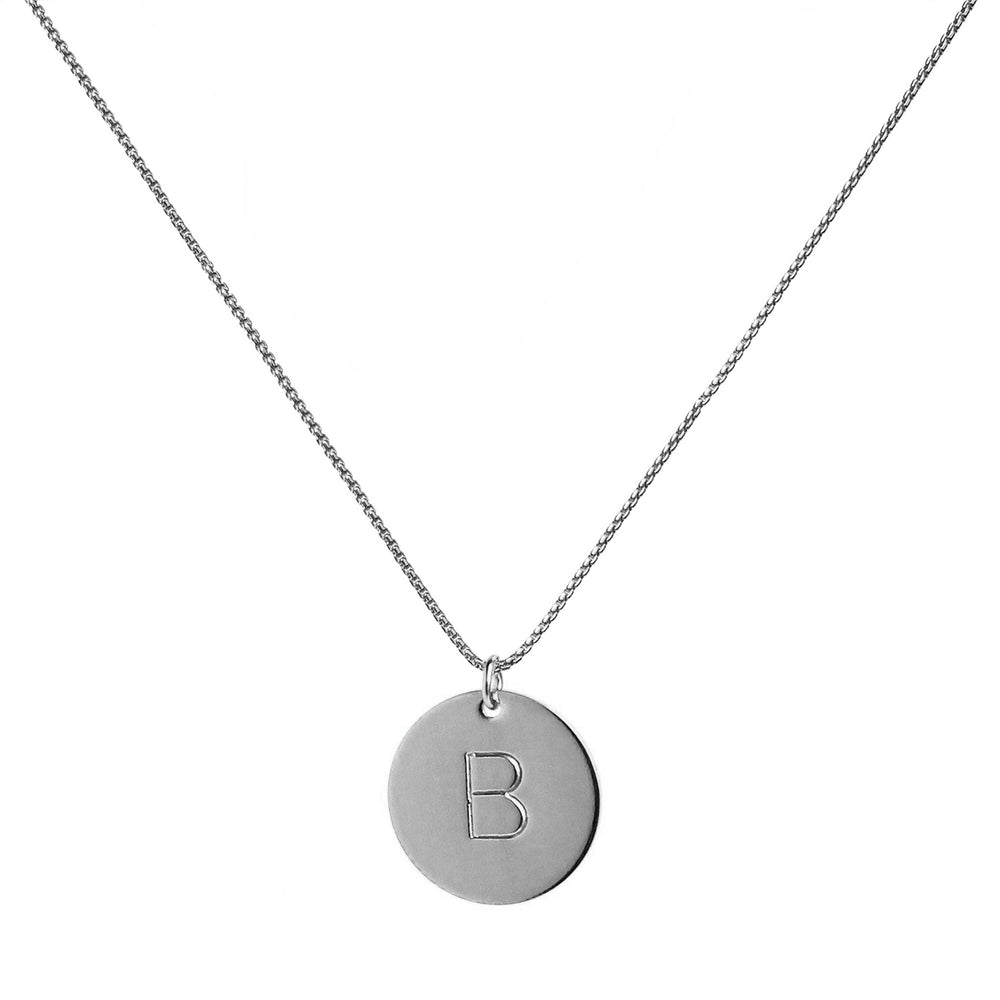 Silver hand-stamped initial disc necklace featuring one personalized pendant on a silver chain, perfect for custom gifts and everyday wear. Handmade by Blooming Lotus Jewelry