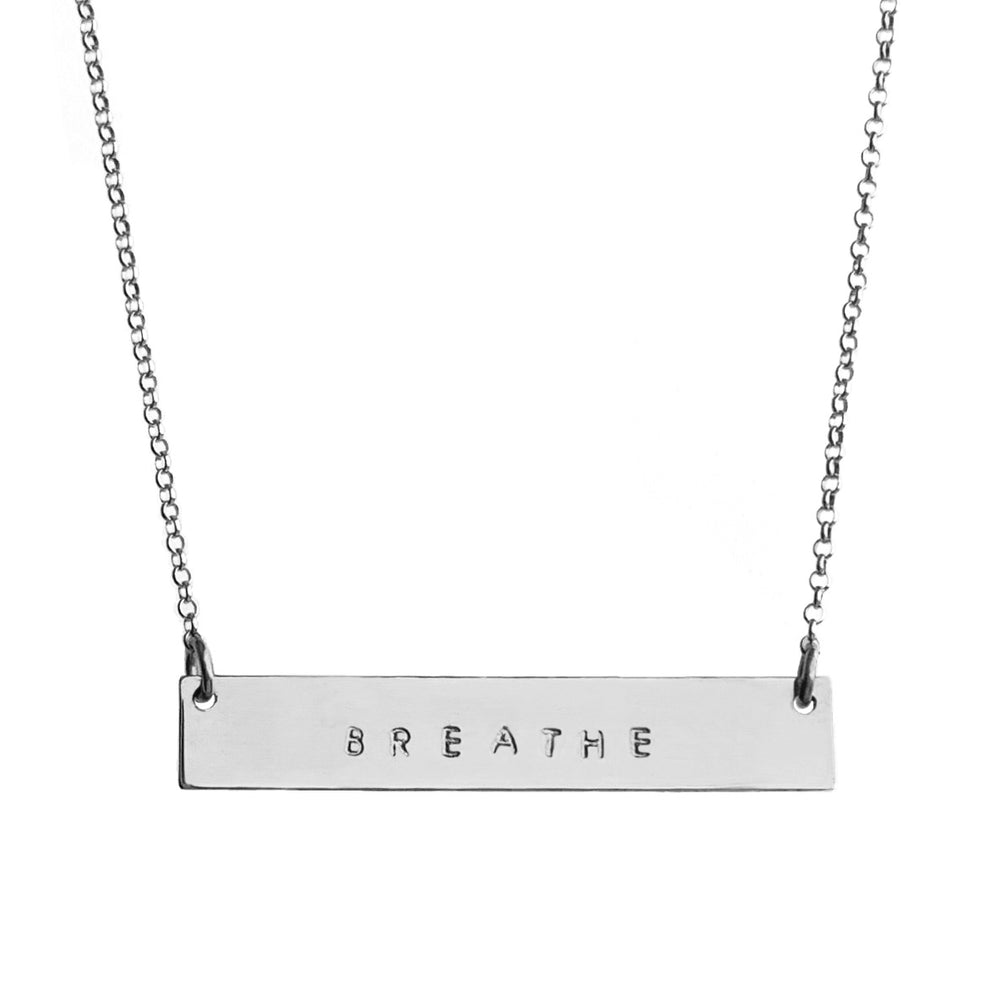 Silver Mantra Bar Necklace engraved with the word 'BREATHE,' hanging on a delicate silver chain, symbolizing mindfulness and simplicity. Handmade by Blooming Lotus Jewelry.