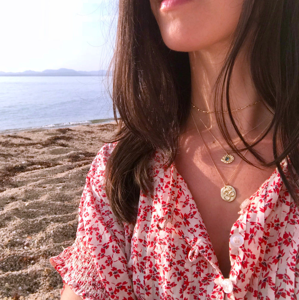 Om and Evil Eye Necklaces on model - beach background - Blooming Lotus Jewelry